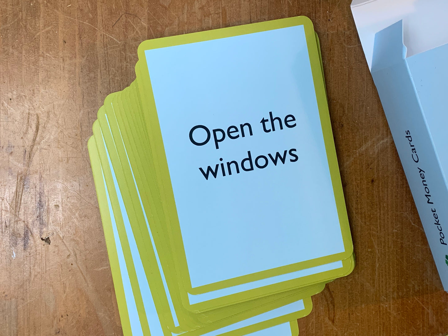 A Pocket Money Card bearing the text 'Open the windows' on a wooden surface